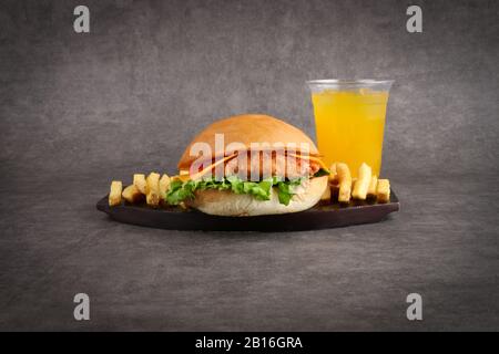 hamburger au poulet croustillant, frites et jus d'orange sur fond gris - repas pour enfants - dîner Banque D'Images