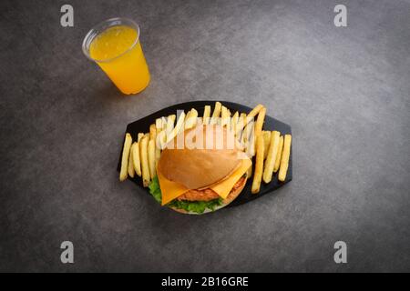 hamburger au poulet croustillant, frites et jus d'orange sur fond gris - repas pour enfants - dîner Banque D'Images