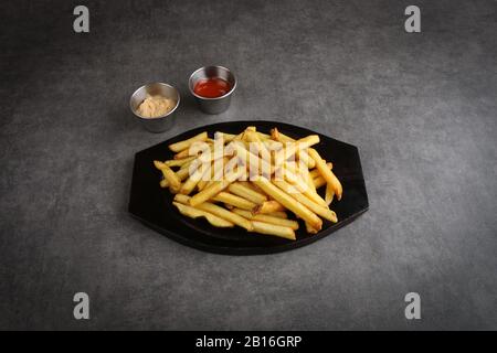 Frites savoureuses avec ketchup et mayonnaise sur fond gris Banque D'Images