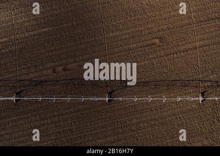 Vue aérienne du système d'irrigation à pivot central sur le champ labouré à partir de drone pov, de l'agriculture et de l'équipement agricole Banque D'Images