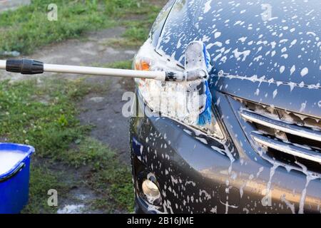Concept de lavage de voiture extérieur, lavage d'une voiture avec une brosse en mousse Banque D'Images