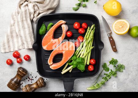 Steaks de saumon non cuits avec légumes sur une poêle à gril, vue de dessus, composition à plat. Concept de cuisine saine, préparation saine des aliments, recette Banque D'Images