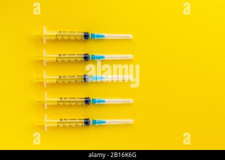 Seringues jetables sur fond jaune vif. Vaccination contre la grippe et le coronavirus. Concept de santé. Injection médicale. Aiguille, dosage Banque D'Images