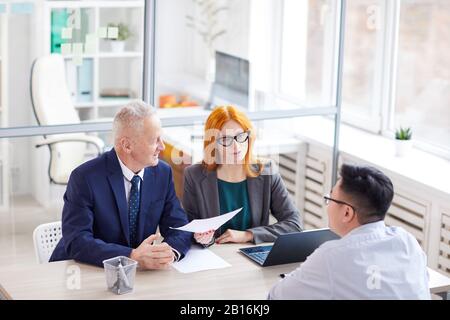 Vue en grand angle de deux gestionnaires qui interviewent un jeune homme pour un poste au bureau, espace de copie Banque D'Images