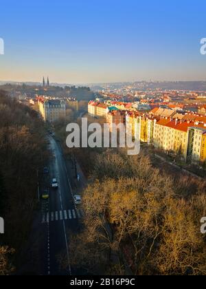 Large route asphaltée avec vue sur le trottoir, arbres d'automne sans feuilles, et paysage urbain sur le côté droit. Journée d'hiver ensoleillée à Prague, république tchèque Banque D'Images