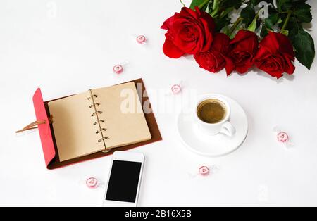 ordinateur portable avec stylo et téléphone, tasse de café et roses sur fond clair, photo macro Banque D'Images