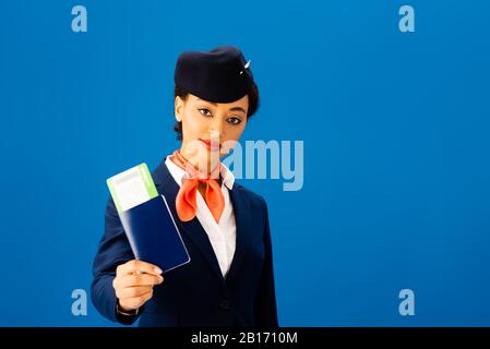 agent de vol afro-américain avec passeport et billet d'avion isolé en bleu Banque D'Images