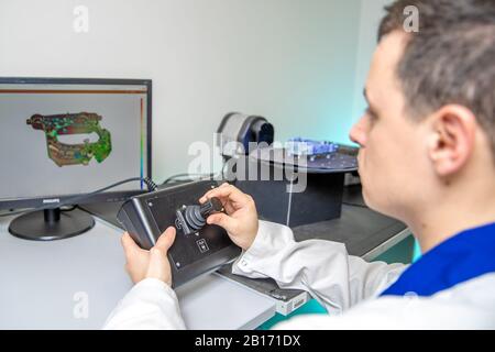 L'ingénieur numérise un composant en plastique de haute qualité avec un scanner tridimensionnel, une plate-forme rotative à l'aide d'un joystick Banque D'Images
