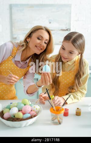 femme heureuse et adorable enfant regardant l'oeuf de poulet peint à pâques Banque D'Images