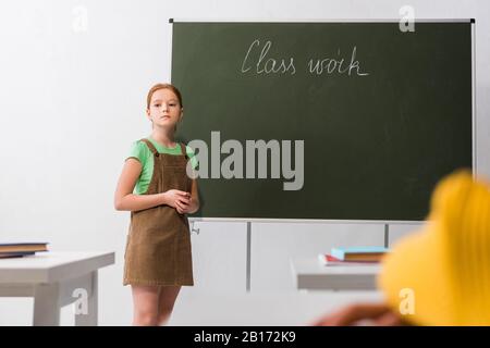 foyer sélectif de la jeune fille bouleversée debout près du tableau de surveillance avec lettrage de travail de classe Banque D'Images