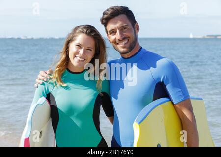 un couple heureux tenant des bodyboards Banque D'Images