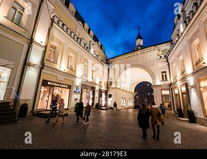 Des vitrines de luxe dans une cour pavée éclairée la nuit, Tretiakov Drive, Moscou, Fédération de Russie Banque D'Images