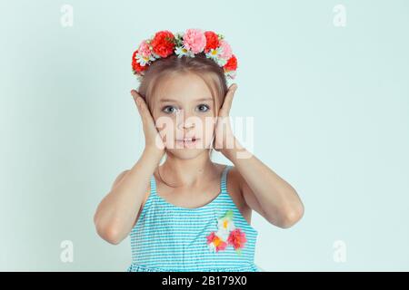 Portrait d'une jolie fille souriante couvrant les oreilles avec ses mains. Joyeux enfant qui ferme les oreilles avec les paumes et regarde l'appareil photo. Jeune garçon caucasien isoler Banque D'Images