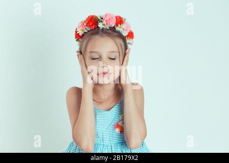 Portrait d'une jolie fille souriante couvrant les oreilles avec ses mains. Enfant heureux avec les yeux fermés qui ferment les oreilles avec les paumes. Jeune enfant caucasien isolé sur une wh Banque D'Images