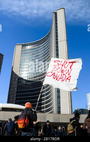 Un manifestant anti-pipeline fait vagues un drapeau à l'extérieur de l'hôtel de ville dans le cadre des manifestations de Shut Down Canada en cours, en solidarité avec le Wet'suwet'en. Banque D'Images