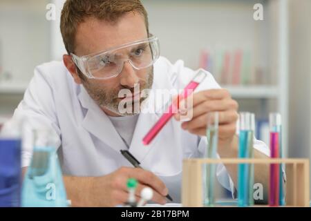 le chimiste man utilise une micropipette pour transférer le liquide dans la bouteille Banque D'Images