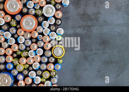 Gros plan sur les extrémités positives des batteries déchargées colorées de différents formats et tailles, vue de dessus, espace de copie. Pile alcaline utilisée sur fond noir Banque D'Images