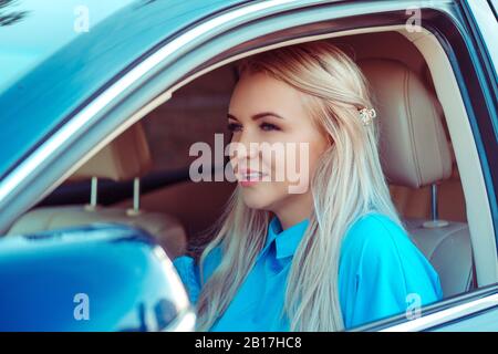 Conduire autour de la ville. Young attractive woman smiling et à tout droit en conduisant une voiture Banque D'Images