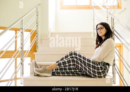 Jeune femme assise détendue sur les escaliers Banque D'Images