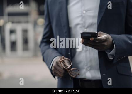 Vue panoramique sur les hommes d'affaires qui détiennent des lunettes et un smartphone Banque D'Images