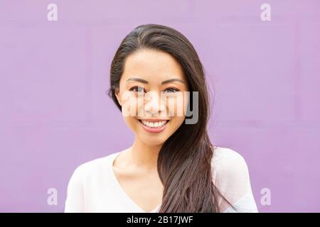 Portrait d'une femme heureuse avec de longs cheveux bruns sur fond violet Banque D'Images