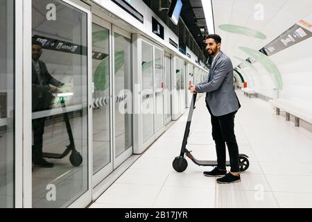 Jeune homme d'affaires avec scooter électrique dans la station de métro Banque D'Images