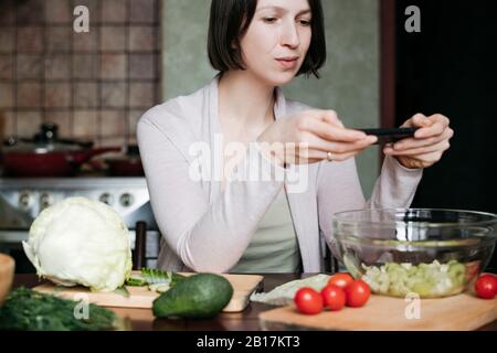 Portrait d'une femme prenant une photo de salade avec smartphone Banque D'Images