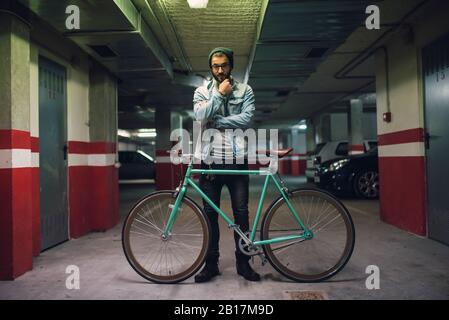 Jeune homme debout dans la maison de parc avec sa fixie vélo Banque D'Images