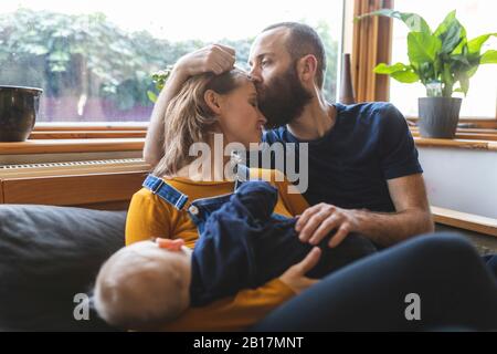 Famille affectueuse sur le canapé avec un petit fils endormi Banque D'Images