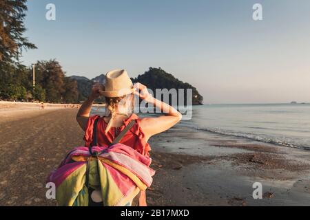 Vue arrière de la femme sur la plage au coucher du soleil, Noppharat Thara Beach, Ao Nang, Krabi, Thaïlande Banque D'Images