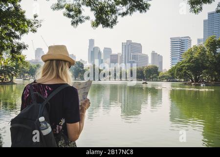 Vue arrière d'une femme regardant la carte dans le parc Lumpini, Bangkok, Thaïlande Banque D'Images