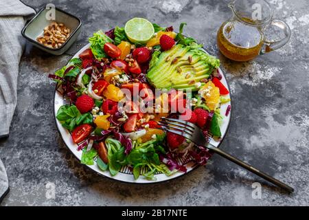 Studio de salade fruitée avec laitue agneaux, radicchio, coeurs de laitue, avocat, tomate, noix de pin, framboises, oranges, citron vert Banque D'Images