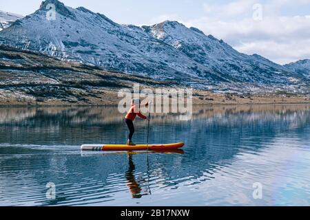 Femme debout paddle surf sur un lac Banque D'Images