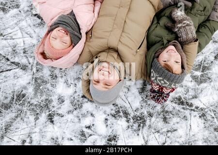 Portrait de famille du père et de deux enfants allongé sur la glace en hiver Banque D'Images