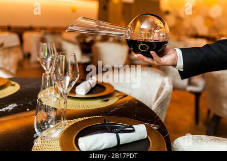 Un serveur qui verse du vin de décanteur dans un verre dans un restaurant raffiné Banque D'Images