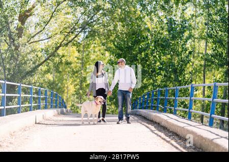 Un couple jouant avec son chien dans un parc Banque D'Images