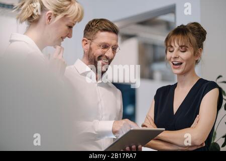 Bonne équipe d'affaires ayant une réunion au bureau partageant une tablette Banque D'Images