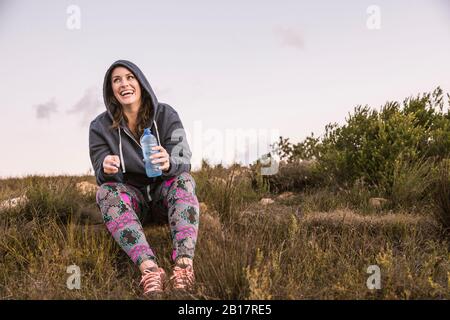 Femme heureuse avec bouteille d'eau ayant une pause de faire des sports dans la campagne Banque D'Images