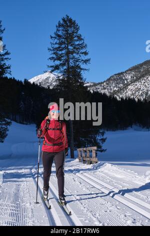 Femme senior qui fait du ski de fond avec des montagnes karwendal en arrière-plan, Bavière, Allemagne Banque D'Images