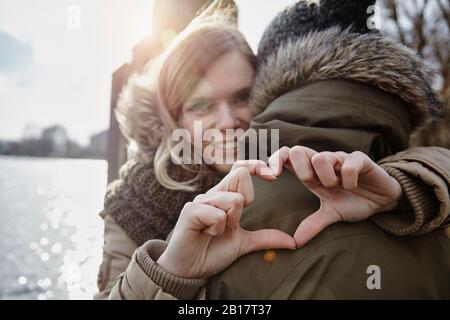 Heureuse jeune femme formant le coeur avec ses mains Banque D'Images