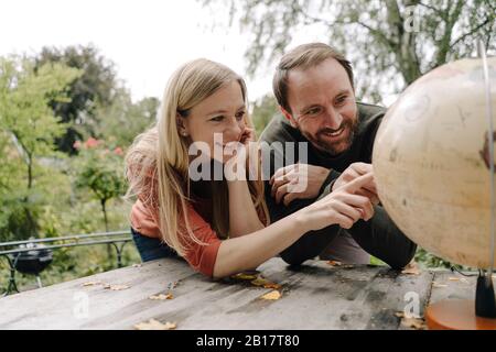 Joyeux couple qui envisage de voyager, en regardant le globe à l'extérieur Banque D'Images