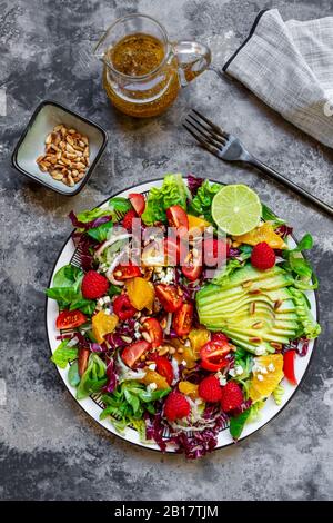 Studio de salade fruitée avec laitue agneaux, radicchio, coeurs de laitue, avocat, tomate, noix de pin, framboises, oranges, citron vert Banque D'Images