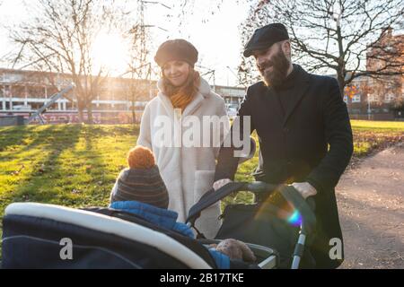 Un couple heureux avec un petit fils dans une poussette au parc Banque D'Images