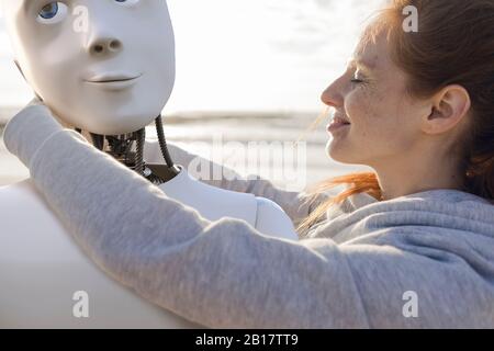 Une femme heureuse embrassant le robot sur la plage Banque D'Images