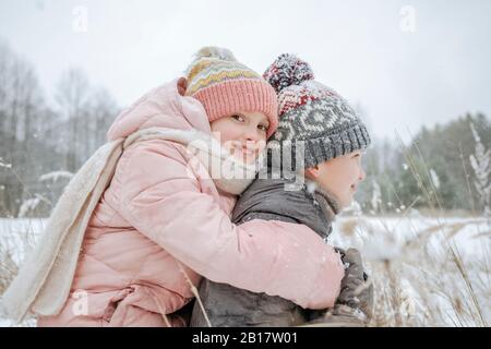 Garçon donnant à sa petite sœur une balade en porcgyback dans la forêt d'hiver Banque D'Images