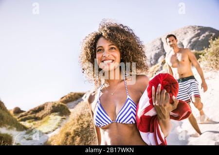 Portait de jeune femme souriante sur le chemin de la plage avec l'homme en arrière-plan Banque D'Images