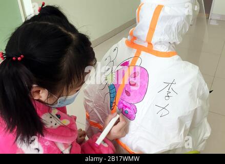 (200224) -- BEIJING, le 24 février 2020 (Xinhua) -- une petite fille colore une peinture sur la combinaison protectrice d'un personnel médical à l'isolement des enfants infectés par le nouveau coronavirus à l'hôpital pour enfants de Wuhan à Wuhan, dans la province de Hubei en Chine centrale, le 20 février 2020. De nombreux enfants avaient peur de voir le personnel médical enveloppé dans des vêtements de protection à l'hôpital pour enfants de Wuhan. Wang Jia, une infirmière de l'hôpital qui aime dessiner, a eu l'idée de dessiner des dessins animés sur des costumes de protection et d'inviter les enfants à les colorer, une façon de les rendre détendu. D'autres membres du personnel médical ont adopté cette idée Banque D'Images