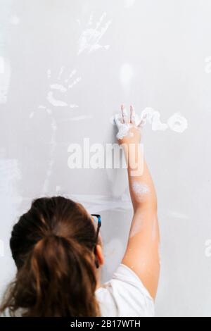 Fille peinture avec son doigt sur un mur Banque D'Images