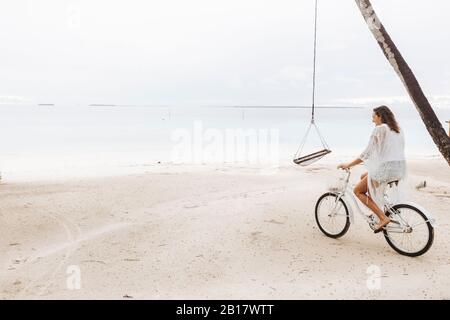 Femme à vélo sur la plage, île de Maguhdhuvaa, atoll de Gaafu Dhaalu, Maldives Banque D'Images