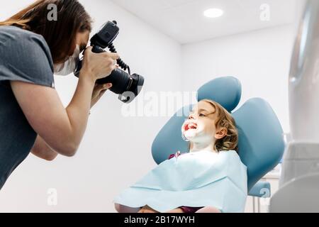 Dentiste prenant photo de fille recevant un traitement dentaire Banque D'Images